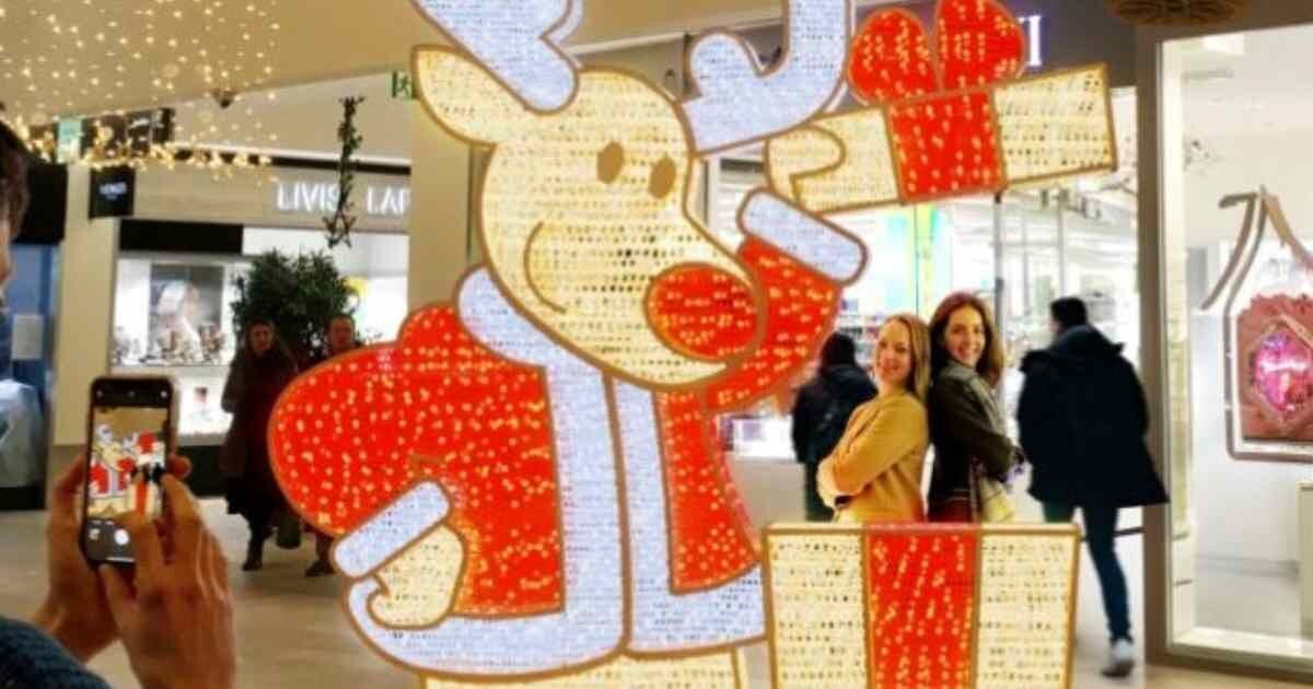 Reindeer display: A glowing reindeer sculpture in a mall with festive decor.